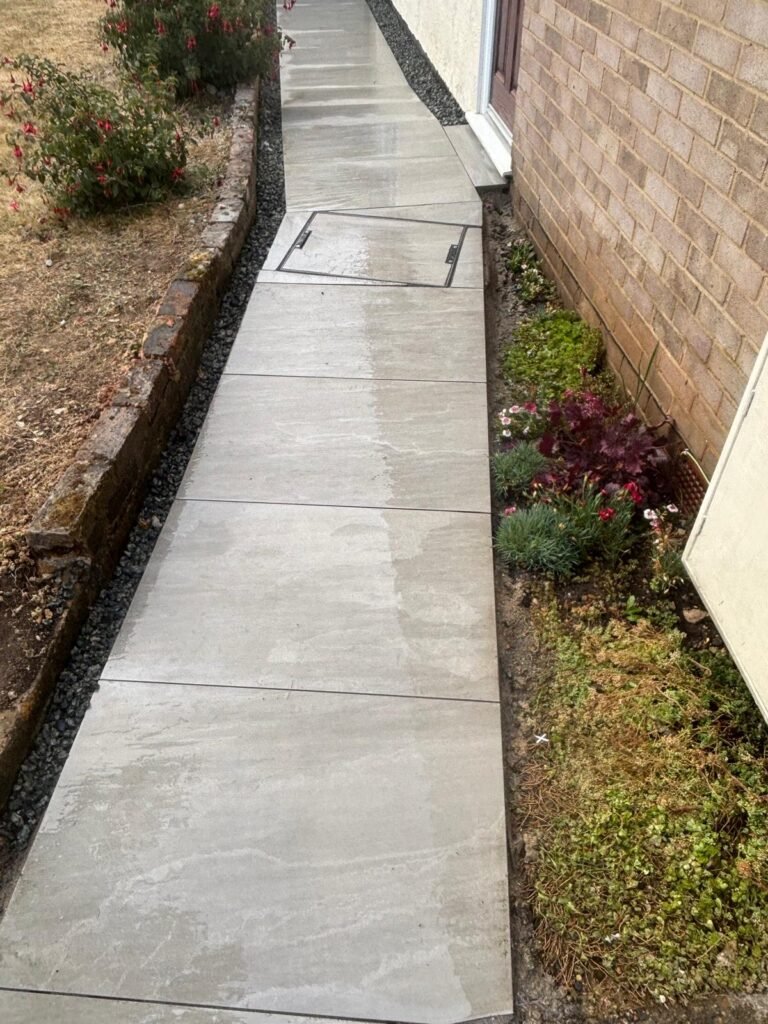 Newly laid concrete side path with clean edging alongside house wall